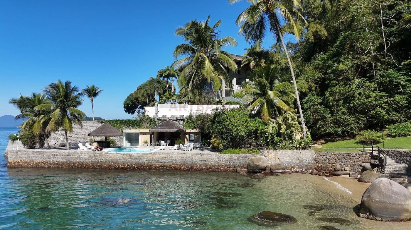Vista panorâmica da praia, piscina e baía com montanhas ao fundo