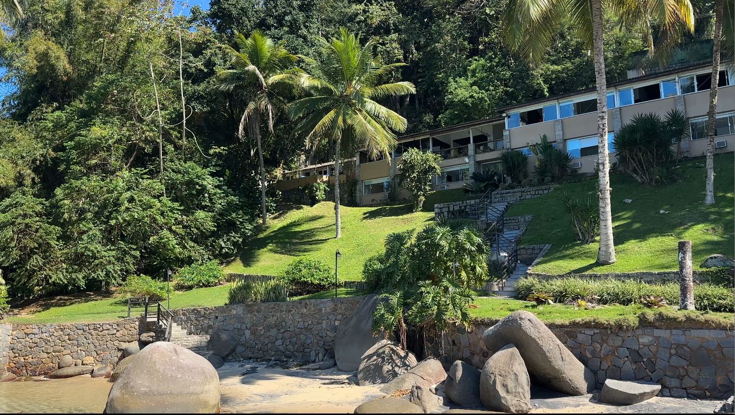 Fachada da residência principal vista da praia, entre coqueiros