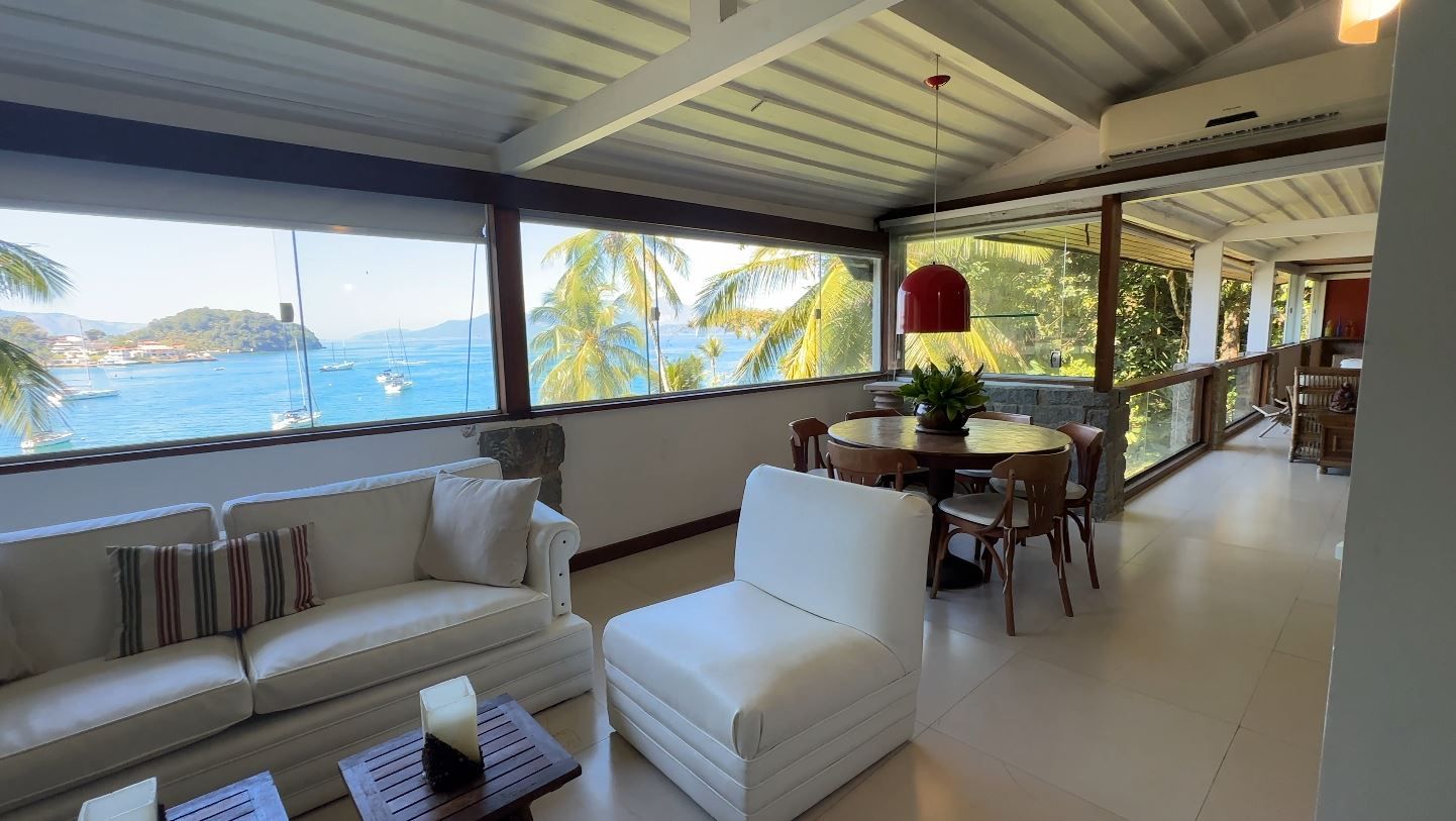 Sala de estar ampla com sofás brancos e vista para o mar