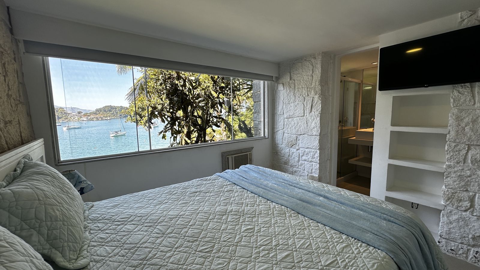 Suíte com cama de casal e vista para os veleiros na baía